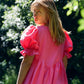 Stunning bright pink dress with puff sleeves and a curved empire seam and tiered hand gathered skirt
